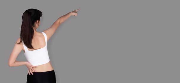 Asian young healthy Fitness woman exercises warm up and point hand direction, studio lighting gray background isolated copy space, concept Woman Can Do athlete Sport - Photo, Image