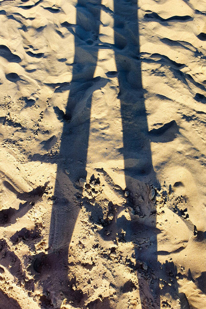 Temiz kumsalda kadın bacakları gölgeleniyor. Dikey fotoğraf, yaşam tarzı, üst görünüm. - Fotoğraf, Görsel