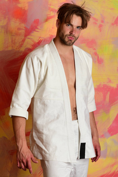 Guy poses in white kimono. Man with confident face - Фото, зображення