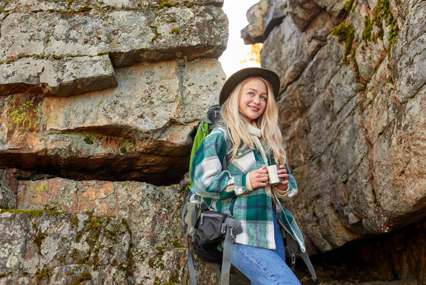 charming blonde female is drinking hot tea during hiking - Photo, image