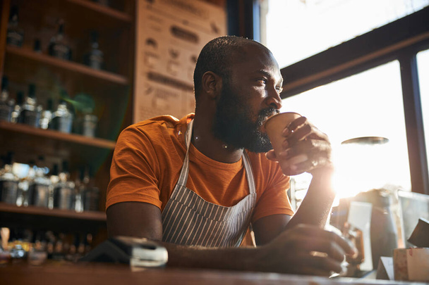 Красивий чоловік бармен п'є каву на роботі
 - Фото, зображення