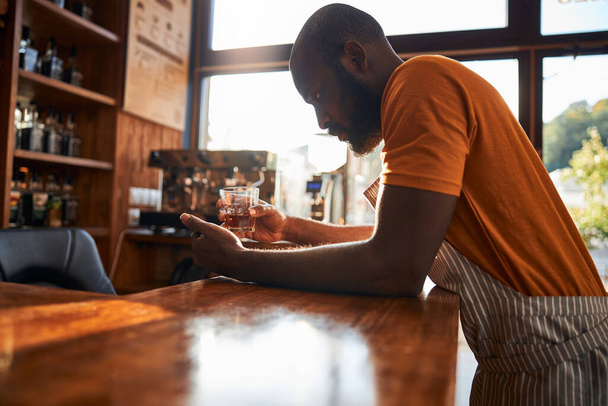 Симпатичный бармен с бокалом виски - Фото, изображение