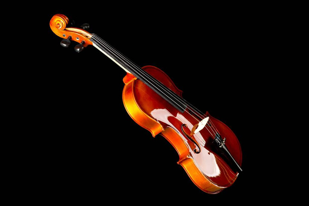 Violín o violín de madera marrón, instrumento musical clásico, aislado sobre fondo negro, enfoque selectivo - Foto, Imagen