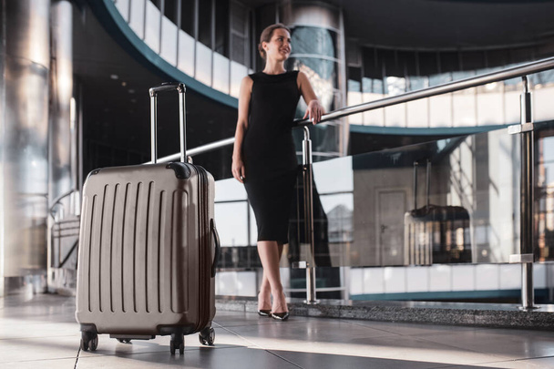 Large and convenient suitcase accompanies a woman while travelling - Foto, imagen