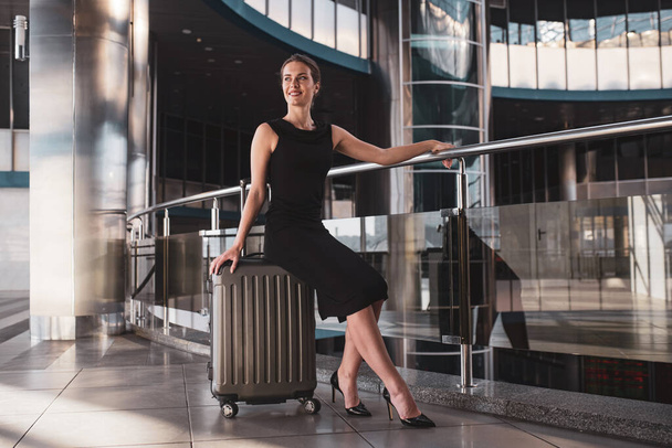 Woman sitting on a suitcase while waiting in the airport - Foto, Imagen