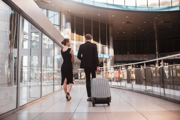 Woman and man carrying their suitcase through the airport - Photo, Image