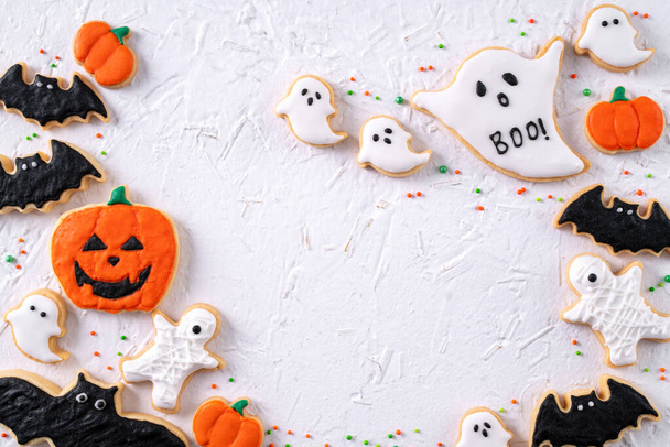 Top view of Halloween festive decorated icing gingerbread sugar cookies on white background with copy space and flat lay layout. - Fotoğraf, Görsel
