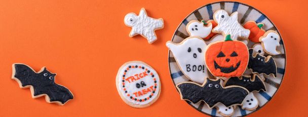 Top view of Halloween festive decorated icing gingerbread sugar cookies on orange background with copy space and flat lay layout. - Foto, Imagen