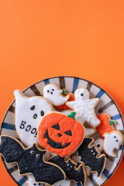 Top view of Halloween festive decorated icing gingerbread sugar cookies on orange background with copy space and flat lay layout. - Valokuva, kuva