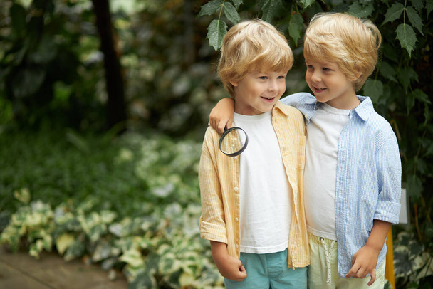 lets go in the garden. two child boys stand aroung plants - Foto, imagen