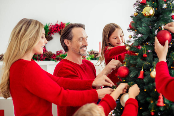 Profile side view portrait of nice attractive big full cheerful family small little kids decorating fir tree christmastime spirit in light white apartment house indoor - 写真・画像