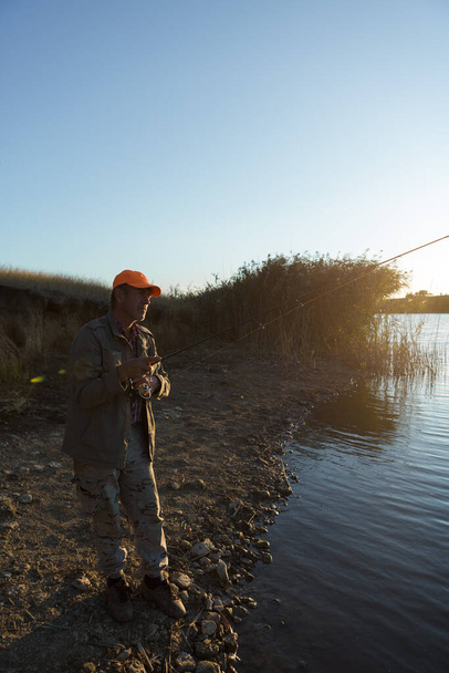 Nehir kenarında duran ve balık tutmaya çalışan bir balıkçı. Spor, eğlence, yaşam tarzı.. - Fotoğraf, Görsel