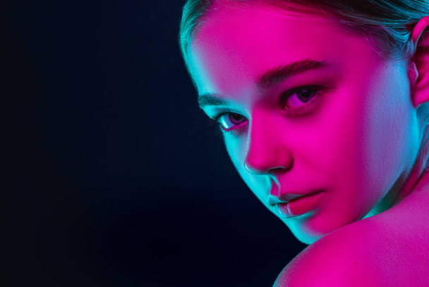 Portrait of female fashion model in neon light on dark studio background. - Fotó, kép