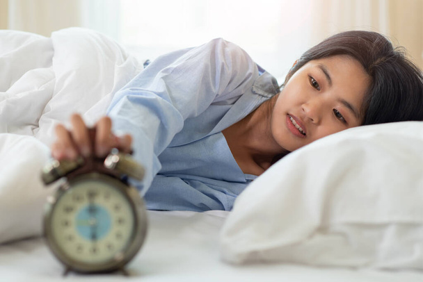 Portrét mladé asijské ženy šokované, když se probudila pozdě ráno, mladá dívka ležící v posteli - Fotografie, Obrázek