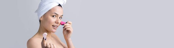 Piękny portret kobiety w białym ręczniku na głowie z gąbką na ciało w świetle różowego serca. pielęgnacja skóry oczyszczanie ekologiczne kosmetyki spa relaks koncepcja. - Zdjęcie, obraz