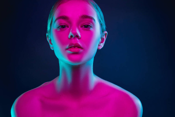 Portrait of female fashion model in neon light on dark studio background. - Foto, immagini