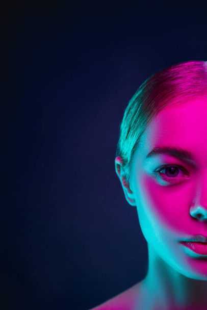 Portrait of female fashion model in neon light on dark studio background. - 写真・画像