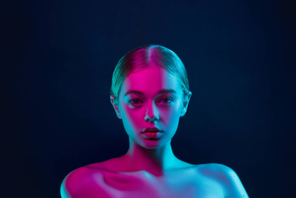 Portrait of female fashion model in neon light on dark studio background. - Foto, immagini