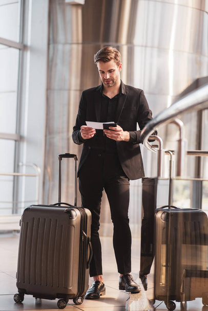 Man reading travel details in his baording pass - Zdjęcie, obraz