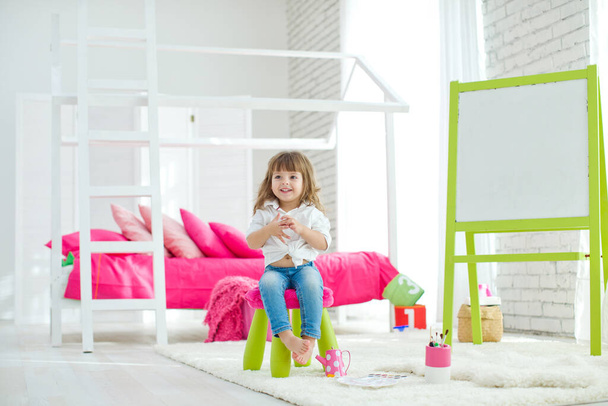 Roztomilá holčička doma na koberci. Vtipné krásné dítě baví v dětském pokoji. - Fotografie, Obrázek