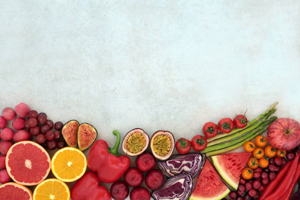 Fruit & vegetable border on mottled background. Foods very high in lycopene and also high in antioxidants, anthocyanins, minerals, vitamins & dietary fibre. Healthy heart & immune boosting food. - Photo, image