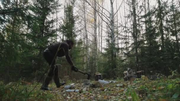 Νεαρός όμορφος άντρας κόβει ξύλα στο δάσος. Ένας ξυλοκόπος κόβει κορμούς σημύδας για καυσόξυλα. Ένας μοναχικός μουσάτος ερημίτης ζει στο δάσος.. - Πλάνα, βίντεο