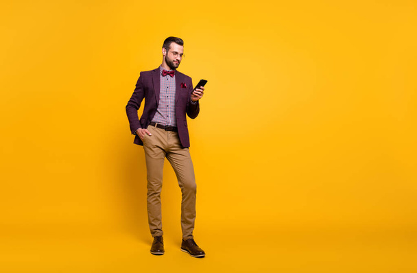 Full length photo of handsome rich clothes stylish guy well-dressed business man browsing telephone read news wear plaid shirt blazer trousers shoes isolated yellow color background - Fotoğraf, Görsel