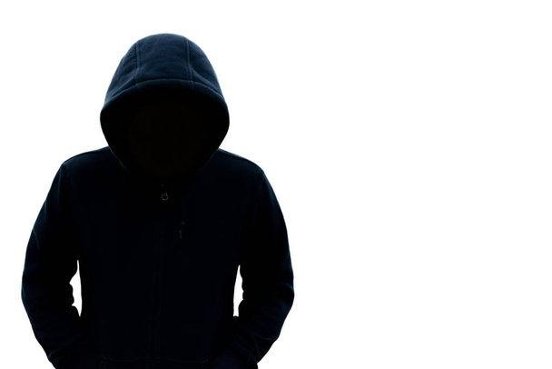 Een man met een kap ziet zijn gezicht niet. Gevaar in het donker Op een witte achtergrond Met een lege ruimte rechts voor tekst of ontwerp - Foto, afbeelding