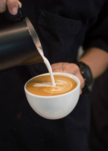 Koffie Latte wordt gegoten in een kopje Latte Art in een coffeeshop. - Foto, afbeelding