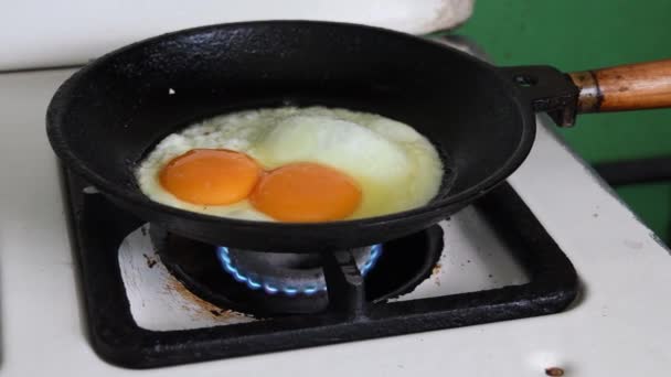 Fried eggs in old cooking skillet at gas stove - Footage, Video