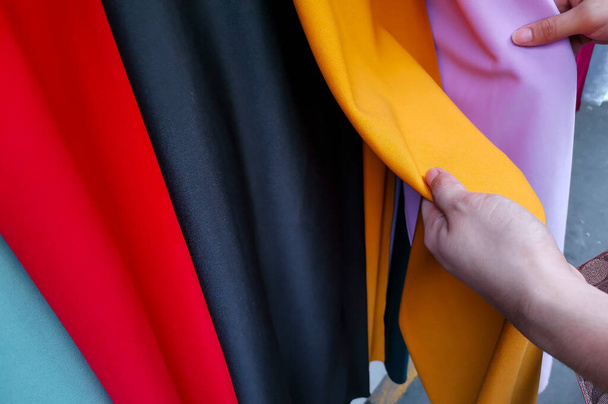 Una mano comprueba algunos textiles en una tienda local en Divisoria, Manila, Filipinas. - Foto, imagen