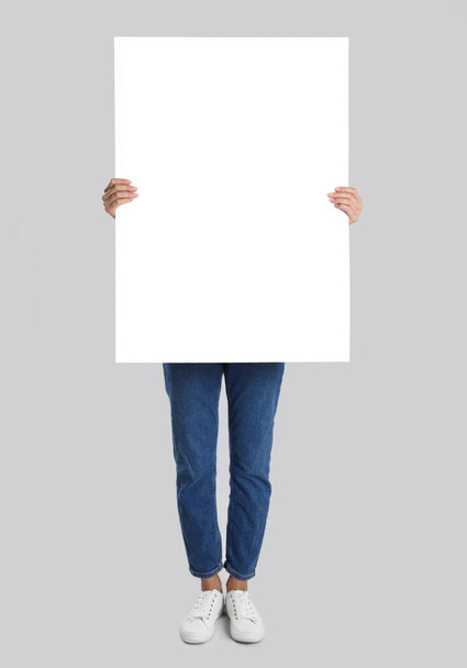 Woman holding blank poster on light grey background - Foto, imagen