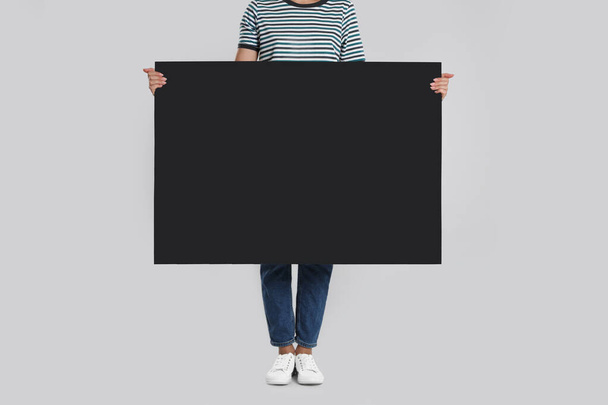 Woman holding blank poster on light grey background, closeup - Фото, изображение