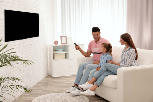 Happy family watching TV on sofa at home - Фото, зображення