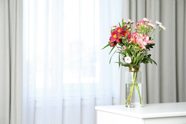 Vase with beautiful flowers on table near window indoors, space for text. Stylish element of interior design - Fotó, kép