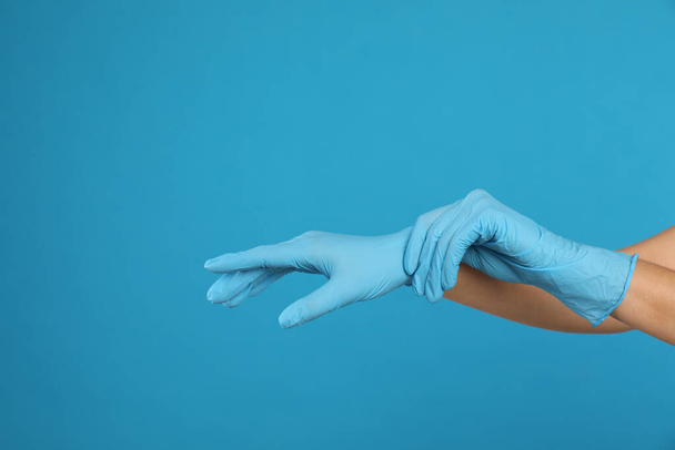 Doctor wearing medical gloves on light blue background, closeup. Space for text - Фото, изображение