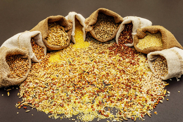 Різновид зернових у мішках ручної роботи. Змішайте незамінні інгредієнти для здорового харчування. Чорний кам'яний бетонний фон, крупним планом
 - Фото, зображення