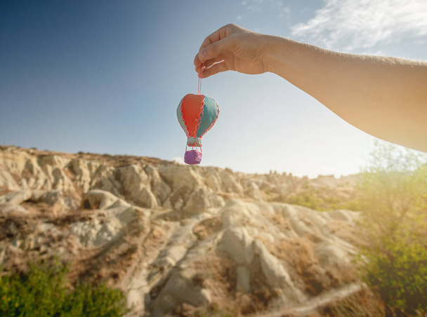 Hand holding souvenir balloon on mountain background - Fotoğraf, Görsel