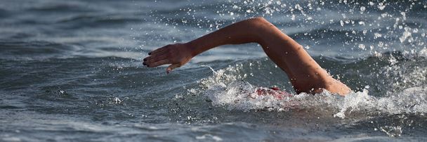 Arm van een zwemmer atleet zwemmen in de oceaan, wedstrijd zwemmen op triatlon - Foto, afbeelding