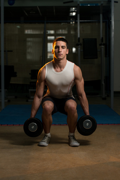 Young Men Doing Squats With Dumbbell In Gym - Foto, afbeelding
