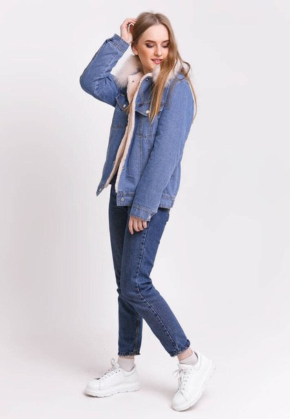 Young Woman in a denim suit with a fur collar on a white background. Clothing advertising concept. - Photo, Image