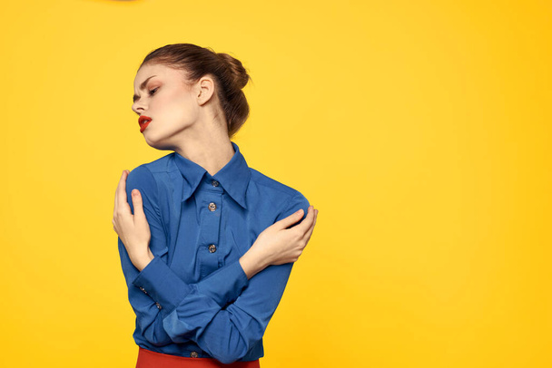 Portrait of a woman in a blue shirt with bright makeup red lips yellow background cropped view - Photo, Image