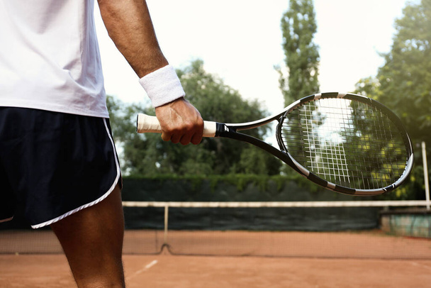 Sportsman playing tennis at court on sunny day, closeup - Fotografie, Obrázek