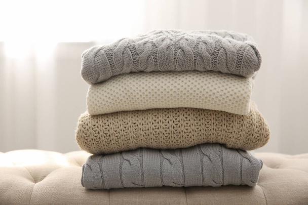 Stack of folded warm sweaters on couch indoors - Photo, image