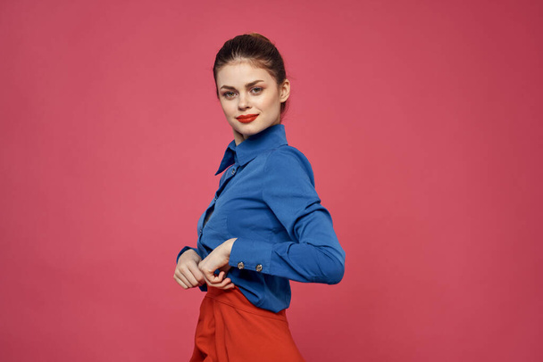 fashionable woman in blue shirt on pink background Red skirt emotions model gesturing with hands cropped view Copy Space - 写真・画像