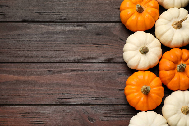 Many white and orange pumpkins on wooden table, flat lay. Space for text - Zdjęcie, obraz