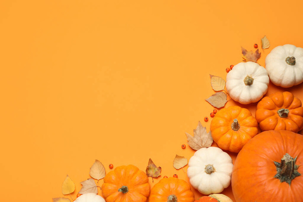 Different ripe pumpkins, autumn leaves and berries on orange background, flat lay. Space for text - Foto, Bild