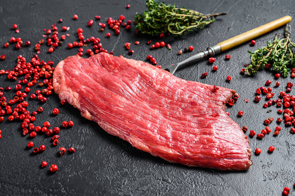 Raw Flank steak with rosemary and pink salt. Fresh Marble beef meat black Angus. Black background. Top view. - 写真・画像
