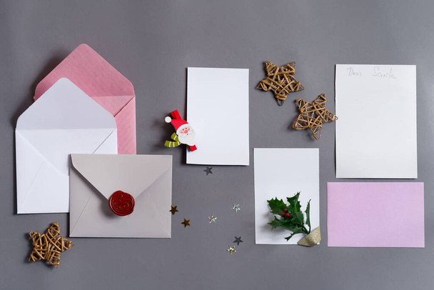 Festive backdrop from colored mock-up paper cards with envelopes and Christmas decoration on a grey background, copy space. Greeting postcard. - Photo, Image