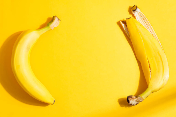 Kreatywna rama owoców z dojrzałego, żółtego banana i skórki na tym samym tle koloru z twardymi cieniami, przestrzeń kopiowania. Widok góry. Wegetariańska koncepcja zdrowej żywności. - Zdjęcie, obraz